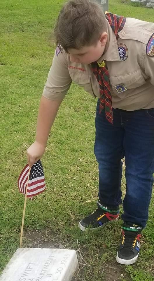 Scout Shaun Friedline putting flags out for Memorial Day at Fairview Cemetery in Shawnee, Ok. 